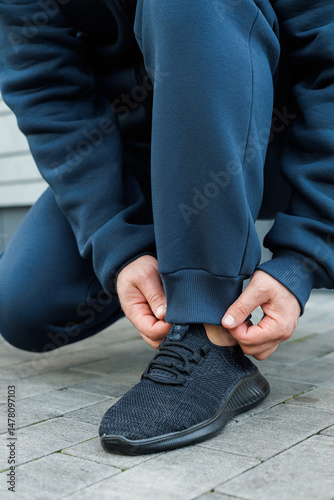 Obraz na płótnie A person is tying the shoelaces on their stylish and modern athletic sneakers while they are dressed in comfortable activewear that is perfect for various types of physical activities and exercises w salonie