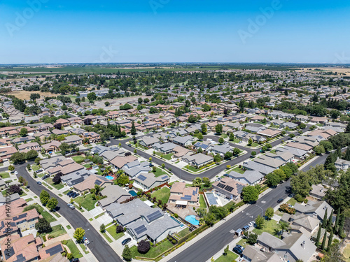 Aerial view of a suburban residential neighborhood in Stockton, California, showcasing rows of single-family homes, streets, and surrounding farmland. Ideal for topics related to urban planning, Calif