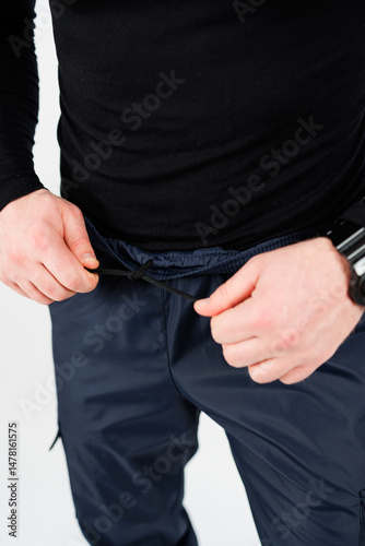 Obraz na płótnie A man is seen carefully adjusting the waistband of his activewear pants to ensure maximum comfort during his fitness session, enhancing his overall workout experience and performance w salonie
