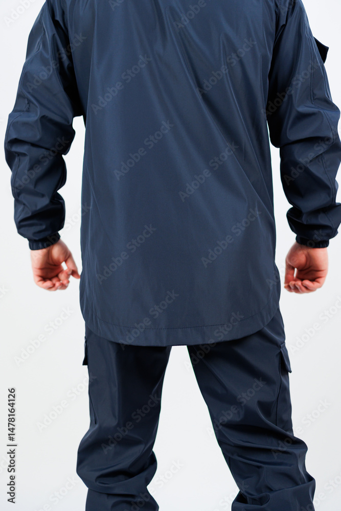 This image showcases the back view of an individual clad in a stylish dark navy workwear jacket and matching pants, designed for both functionality and fashion in active environments