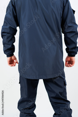 Obraz na płótnie This image showcases the back view of an individual clad in a stylish dark navy workwear jacket and matching pants, designed for both functionality and fashion in active environments w salonie