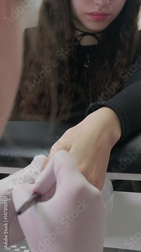 Manicure process in a beauty SPA salon close up. Professional manicurist in gloves paint nails with natural gel polish in luxury salon. Concept nails and hands care 