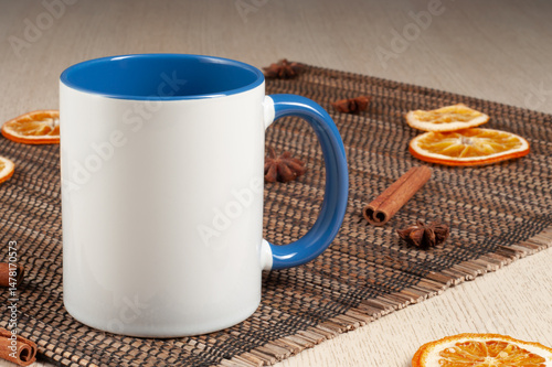 Blank two-tone 11oz mug on on the table. Mug with warm spices like cinnamon, star anise, dried orange. Blue handle. Mug mockup