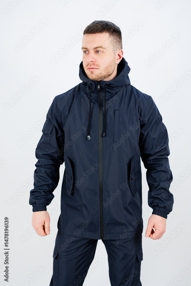 Fototapeta premium A stylish man wears a fashionable navy blue waterproof jacket with a convenient hood and zipped front, ideal for outdoor fashion and an active lifestyle, ensuring comfort and practicality