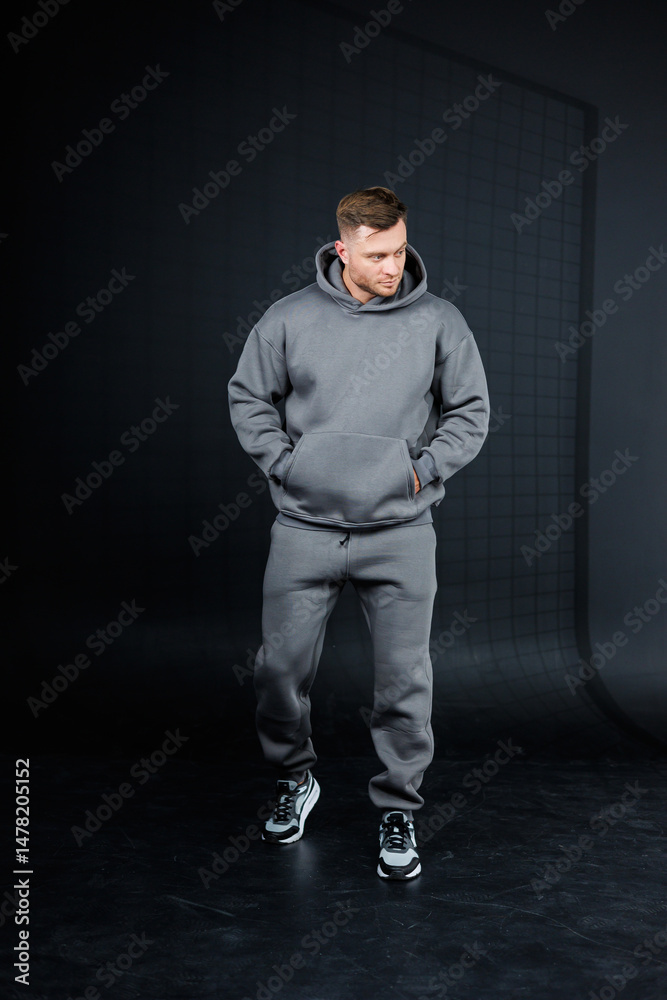 A fashionable young man wearing a modern gray hoodie and matching sweatpants, perfect for showcasing an urban fashion collection that highlights the latest trends in activewear apparel