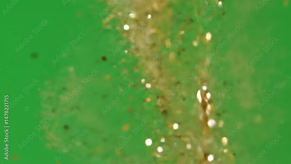 Gold glitter falling against a vibrant green screen for visual effects use
