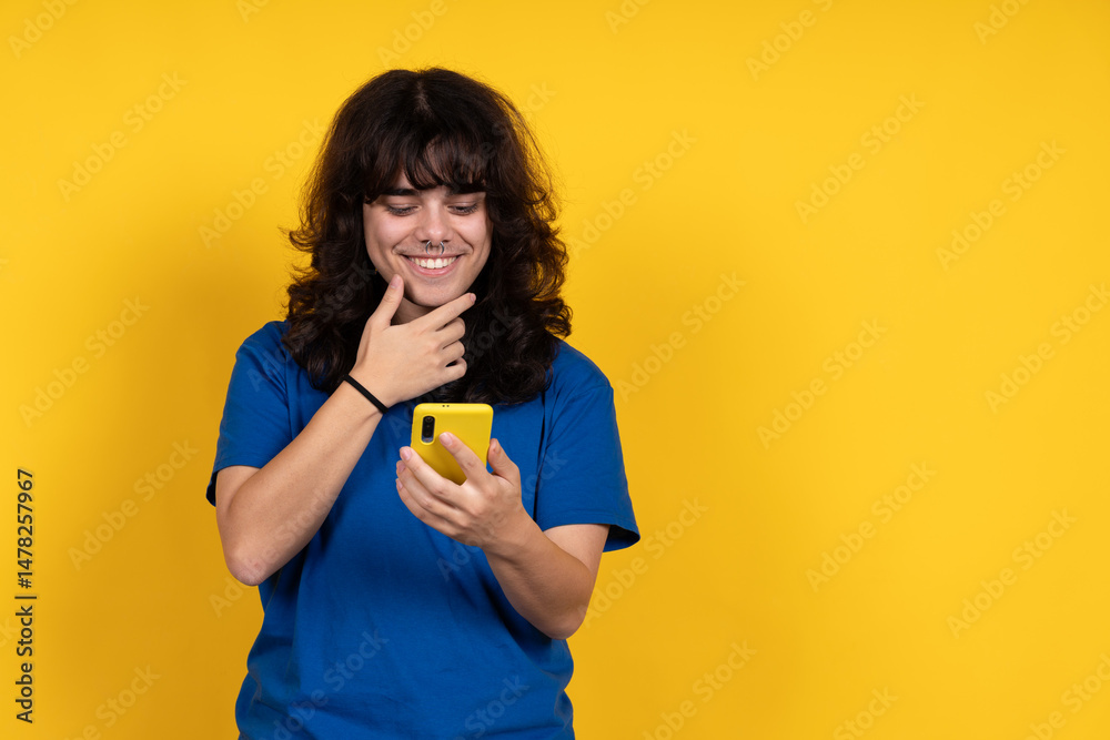 Young person smiling and using smartphone on yellow background Young person smiling and using smartphone on yellow background