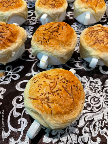 An attractive top view of several bowls of Zuppa Soup, each lined with golden brown crispy puff pastry topped with melted cheese.