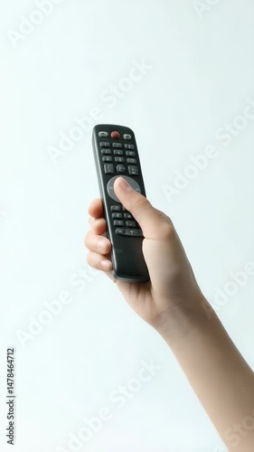 Wallpaper Mural Hand holding black remote control, pressing round button on white background with plain backdrop in vertical orientation Torontodigital.ca