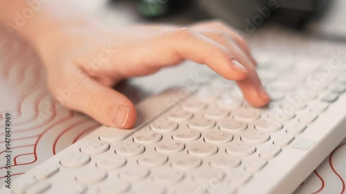 Hand pressing keys on stylish wireless keyboard during remote work or online learning. Modern digital lifestyle, freelance routine, technology in everyday life, creative workspace.