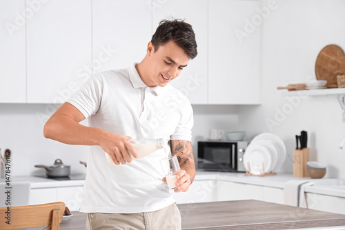 Young man pouring milk from...