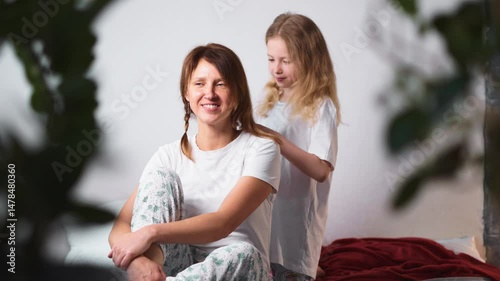 Girl focused on helping her mom with haircare at home, showing initiative and kindness. Moment captures empathy, role-play, and early development of responsibility and affection.