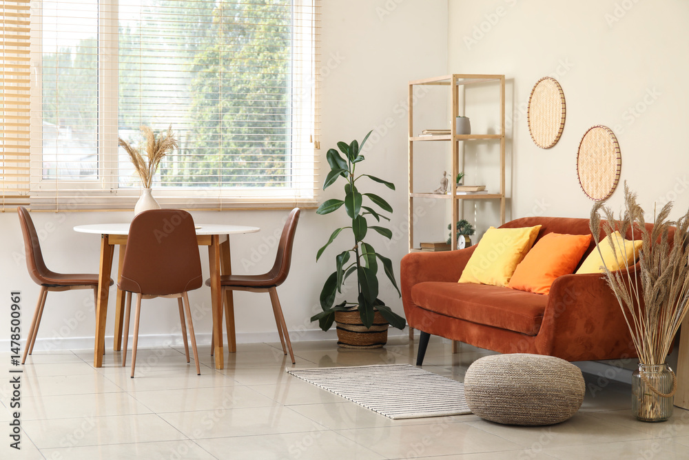 Fototapeta premium Dining table, sofa and houseplant in interior of living room