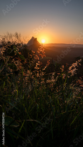 Sunset glow over wild grass and volcanic peaks in Queensland, Australia