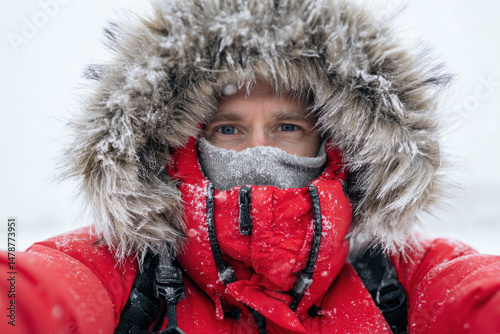 Man wearing red puffy jacket takes selfie in very cold conditions