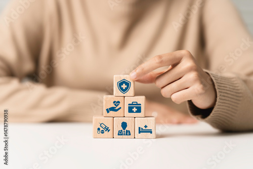 Health insurance concept. Hand arranging cubes wooden block with healthcare medical icon. Access to welfare health, safety first, protection, health, regulation and insurance for banner, background.