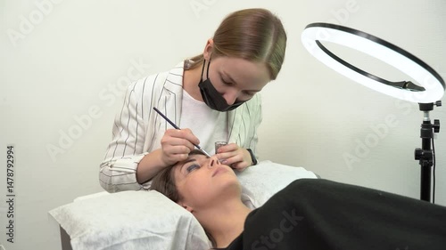 The master laminates the eyelashes of a young beautiful girl. 4K close-up