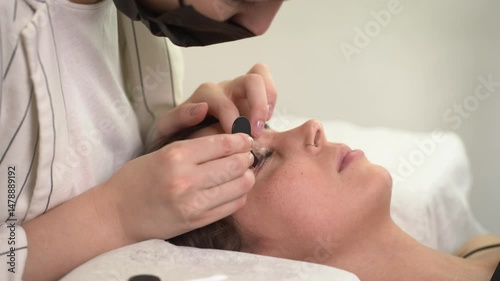 The master laminates the eyelashes of a young beautiful girl. 4K close-up