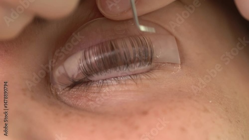 The master laminates the eyelashes of a young beautiful girl. 4K close-up