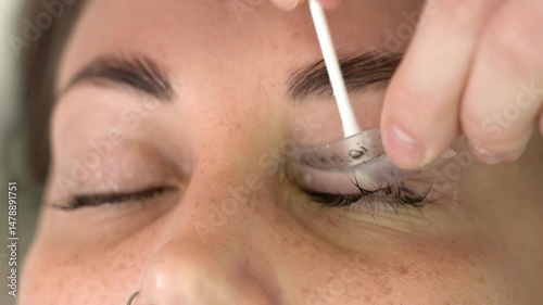 The master laminates the eyelashes of a young beautiful girl. 4K close-up