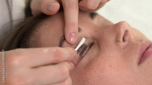 The master laminates the eyelashes of a young beautiful girl. 4K close-up
