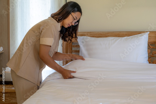Hands of hotel maid making the bed in the luxury hotel room ready for tourist travel.