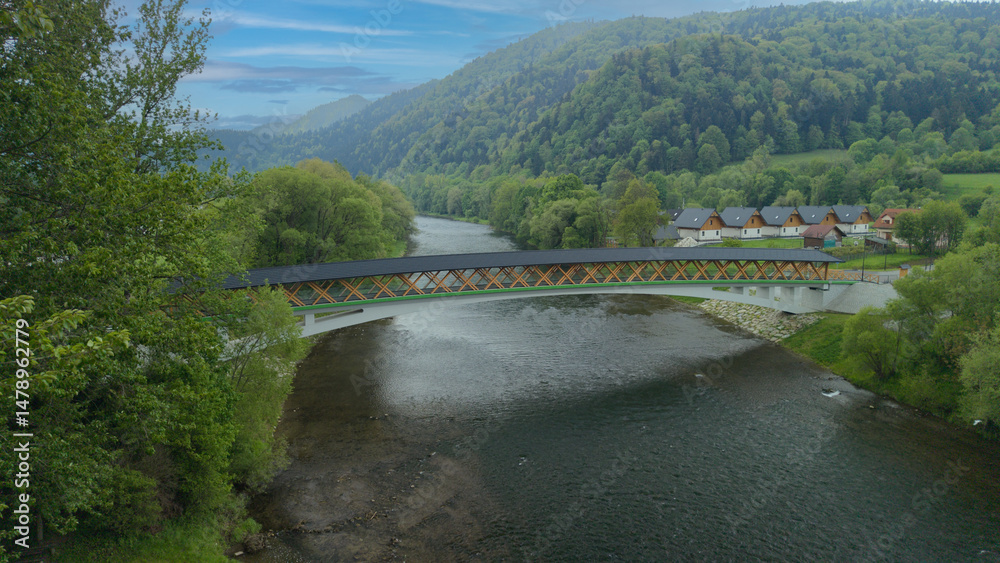 Fototapeta premium The pedestrian and bicycle bridge known as the “Broken Bridge” spanning the Dunajec River in the picturesque Pieniny Mountains, close to the town of Kroscienko, Poland.
