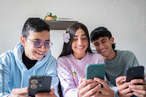 Group of latino friends smiling and using smartphones together