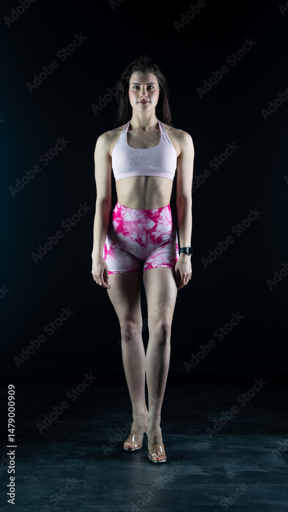 Fototapeta premium Young beautiful woman with athletic body on dark background. Fitness girl 