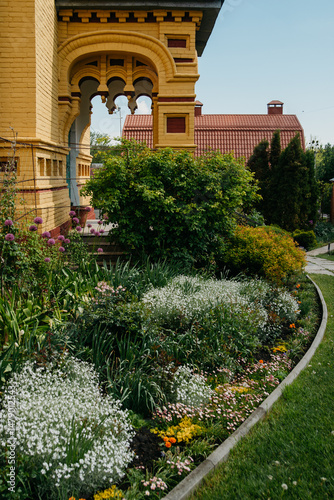 Part of a classic wooden building with decorative carvings against the backdrop of a well-kept garden