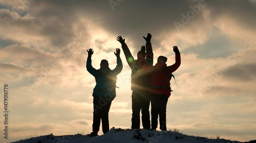 Alaskan travelers go to top of snowy hill rejoice in victory against winter sunset. Business teamwork, victory and success. Tourists met on top of success. Victory success business people team work