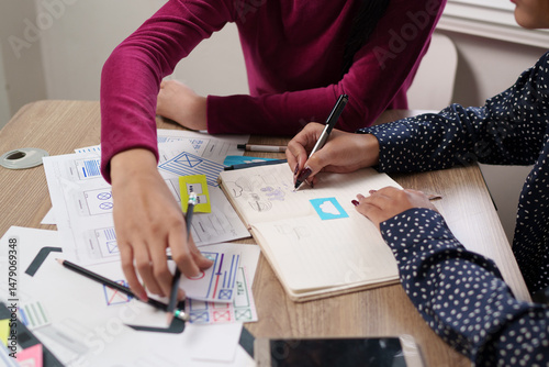 User Interface Designer Collaboration Adult Asian Women Sketching Mobile App Layout with Pen and Paper on Desk for Website Design
