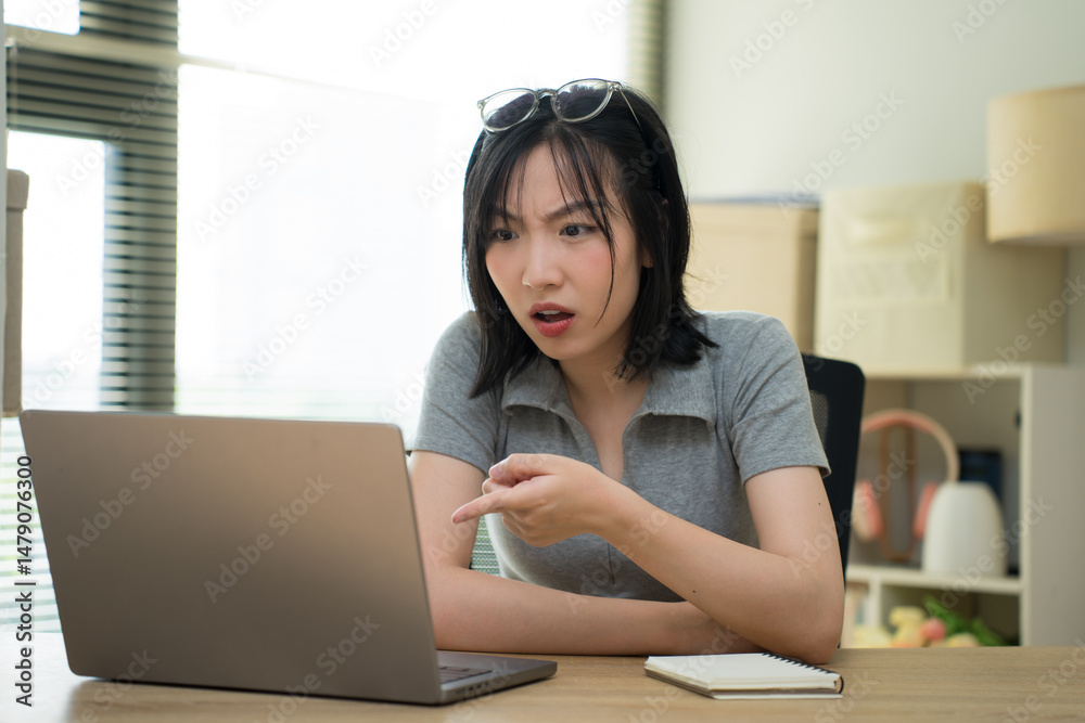 Obraz premium Engaging Asian woman discussing ideas while working on a laptop at home during daytime
