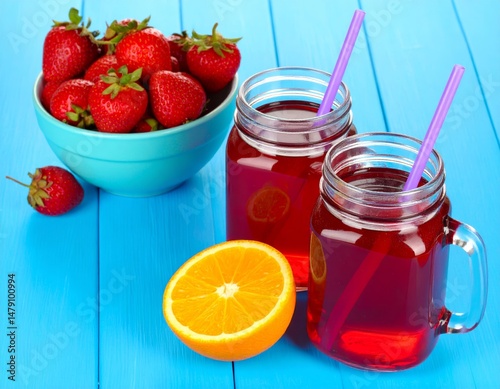 Wallpaper Mural Blue table with red tea in jars, purple straws, strawberries in bowl, and orange slice. Torontodigital.ca