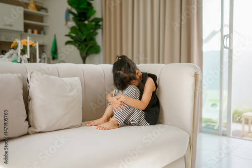 Bored disappointed little Caucasian girl schoolgirl daughter kid hug knees alone home thinking domestic violence school bullying feeling lonely depressed sad upset offended child suffering from abuse