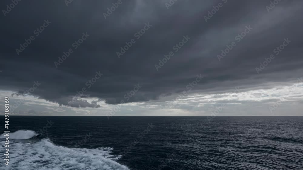 Menacing dark clouds looming over turbulent seascape, massive wave rising and surging with raw elemental power against deep blue horizon Menacing dark clouds looming over turbulent seascape, massive wave rising and surging with raw elemental power against deep blue horizon