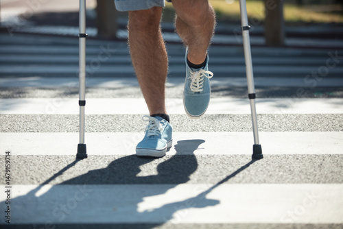 man trying to walk on street with the help crutches