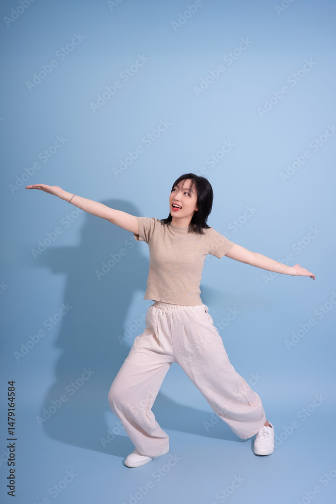 Obraz premium Dancer striking a lively pose against a soft blue background in a creative studio setting during daylight