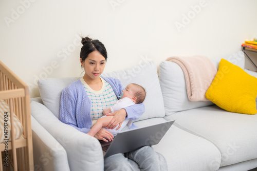 Mother working from home using laptop while caring for baby