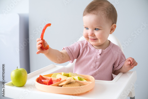 cute baby eating solid food sitting in a baby chair. weaning