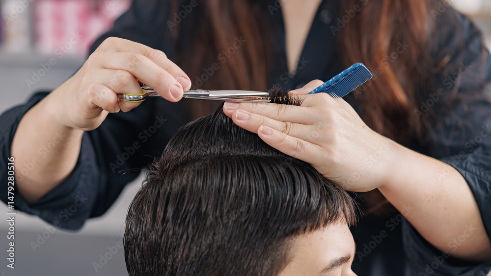 Naklejka premium Stylist trims male hair with scissors and comb during precise grooming in salon.