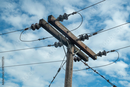 Wooden electric pole reinforcement with steel ropes in blue sky closeup