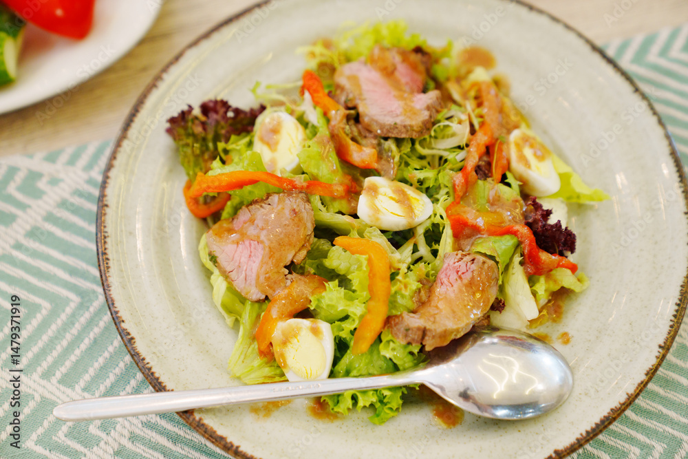 A plate of meat salad made from lettuce, quail egg, vegetables and steak. A plate of meat salad made from lettuce, quail egg, vegetables and steak.