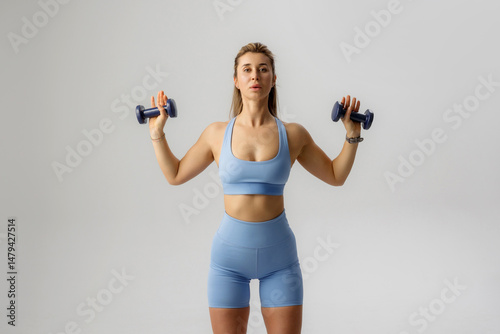 Woman exercising with dumbbells in a fitness studio during daytime workout session