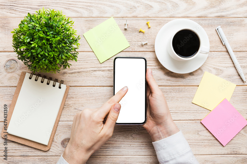 Obraz premium Top view of woman hands holding smart phone with blank copy space screen for your text message or information content. woman hand using phone white screen on top view