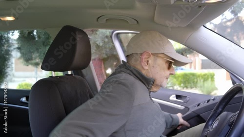 An elderly man gets into a car and fastens his seat belt for added safety and protection.