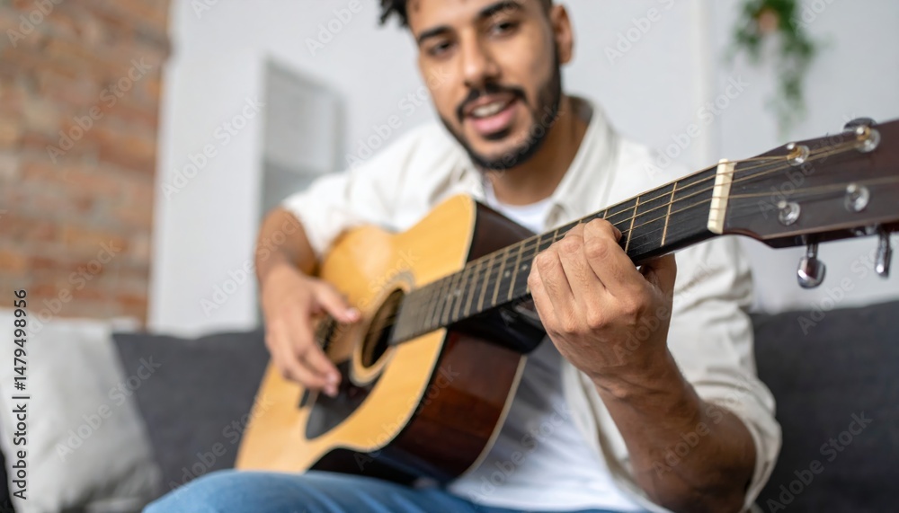 Obraz premium Happy man playing guitar at home on the sofa