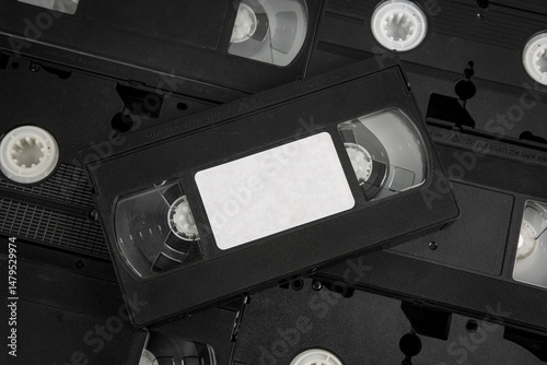 Stacked VHS tapes with a blank white label, black cassette.