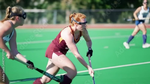 A skilled female field hockey player showcases her offensive prowess as she advances with the ball while closely pursued by relentless defenders from the opposing team
