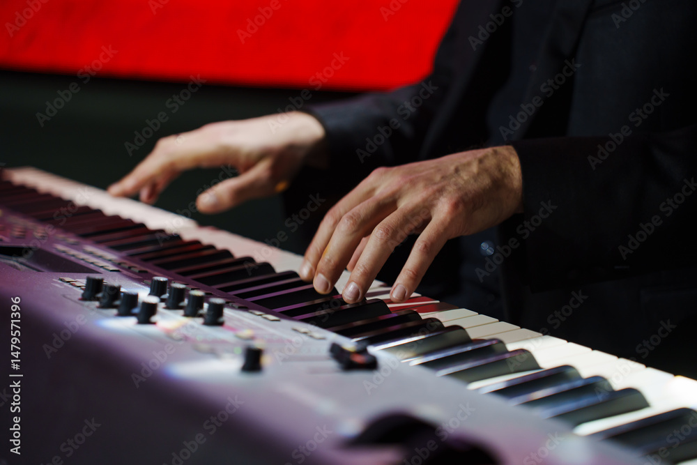 Obraz premium Men's hands play the keys of an electronic piano.